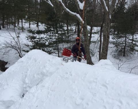 An expert clearing snow from a roof